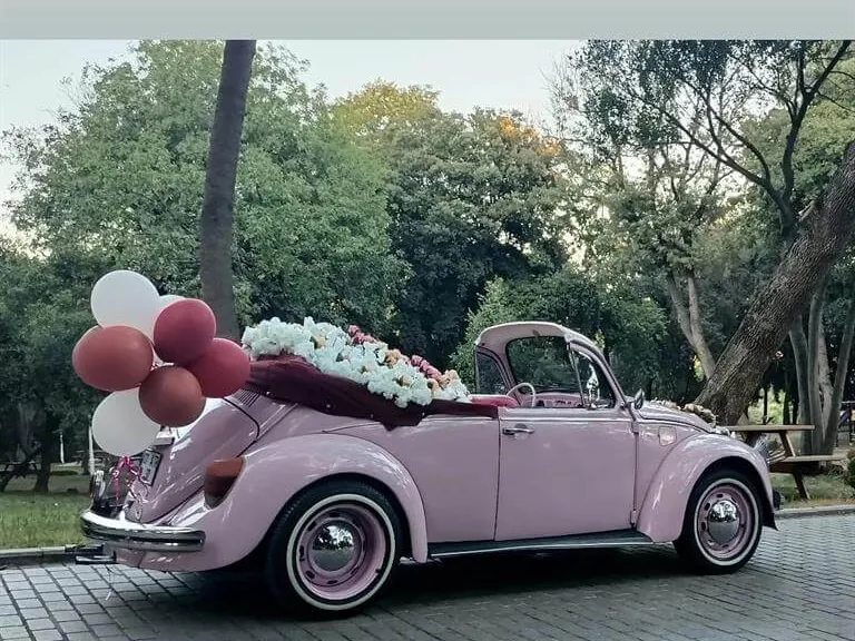 Balon, tül ve çiçeklerle süslenmiş pembe cabrio Vosvos gelin arabası park içinde